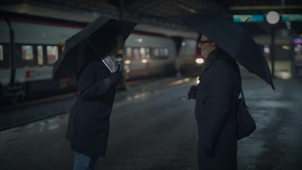 Gece Yarısının Karanlığında Bir Tren Istasyonunda Şemsiyelerin Altında Iki Kişi — Stok video