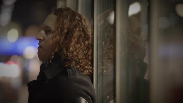 一个留着卷发的男人站在玻璃门旁边 在不同的背景下记录着他的沉思心情 拍了许多照片 — 图库视频影像