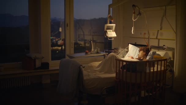 病院のベッドで横たわっている若いアフリカの母 誕生後新生児を抱えている — ストック動画