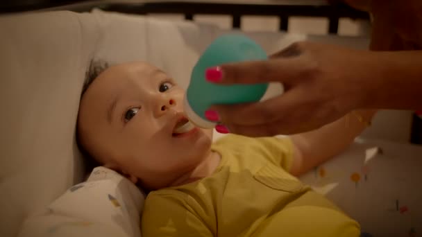 母親は自宅でベビーベッドで横たわっている幼児を養っています 高品質の4K映像 — ストック動画