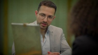 Satış temsilcisi kasa dairesindeki müşteriyle konuşuyor. Mevduatı açıklıyor.