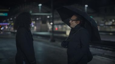 Geceleri tren istasyonunda tartışan kızgın bir çift.