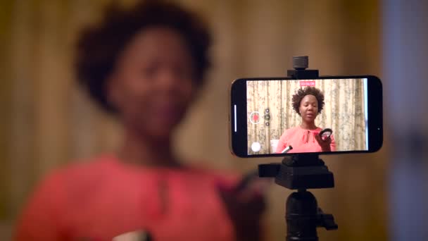 女性は家庭でスマートフォンで美容製品ビデオを録画するインフルエンサーを作ります — ストック動画