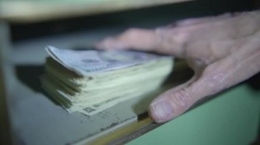Banka kasasında yığınla parayı güvenceye almak için el feneri kullanan bir adam, finansal güvenlik faaliyetlerine girişiyor..
