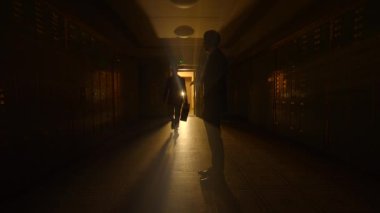 Karanlık odada buluşan iki kişi şüpheli bir şekilde parayı teslim ediyor.