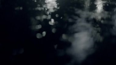 Şehir caddesine yansıtıcı bir gece yağmuru yağar. Parlak ışıklar ve ıslak kaldırımlarla kasvetli bir atmosfer yaratır.