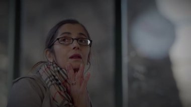 Anne, Oğlu Tren İstasyonu 'nda Bekliyor. Saate danışmak için saati kontrol ediyor.