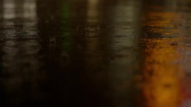 Geceleri ıslak bir cadde, şehrin ışıklarını yansıtır. Kasvetli bir dokusu olan, atmosferik bir şehir manzarası yaratır.