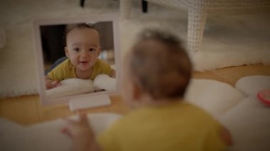 Çocuk çocuk aynaya bakıyor kendini yerde yatarken izliyor