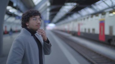 Tren istasyonunda siyah kıvırcık saçlı genç adamın yaşam tarzı portresi. Yüksek kalite 4k görüntü