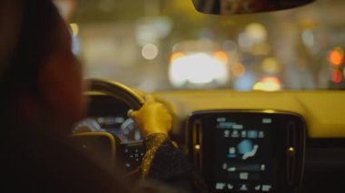 Gece vakti şehirde siyah kıvırcık saçlı, araba kullanan bir kadın trafik lambası. Yüksek kalite 4k görüntü