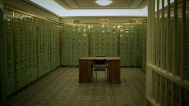 Oda, şüpheli ses ekipmanlarıyla dolu bir banka kasasına yerleştirilmiş dolaplar ve bir masa ile dolu. İç dizaynda sert ahşap döşemeler ve metal dolaplar var.