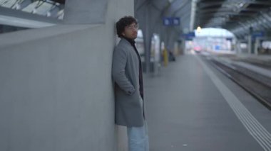 Tren istasyonunda siyah kıvırcık saçlı genç adamın yaşam tarzı portresi. Yüksek kalite 4k görüntü