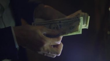 Yakın plan çekimler, loş ışıkta para saymak, zenginlik, finans ve ekonomik işlemleri gözler önüne sermek.