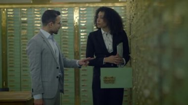 Güvenli bir banka kasasında kasalarla dolu belgeleri tartışan iki profesyonel..