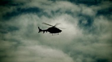 Çarpıcı bir helikopter silueti dramatik bulutlu bir gökyüzünde uçuyor, çeşitli medya kullanımları için mükemmel..