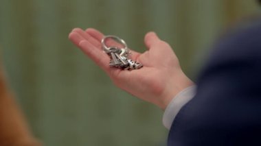 Bir kişi, resmi bir ortamda anahtarlarını verir, iş, işlem ve anlaşma kavramlarını tasvir eder.