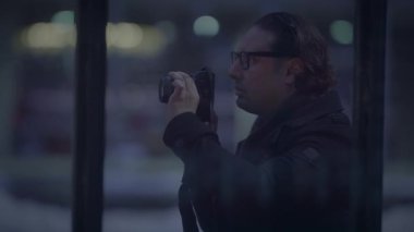 Yetenekli bir fotoğrafçı kendini şehrin gece atmosferini yakalamaya adamış, kamerasıyla manzaraya odaklanmış.