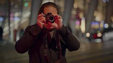 Şehir gece hayatının özünü yansıtan gözlük takan bir sokak fotoğrafçısı, şehrin sinema ışıklarını vurguluyor.