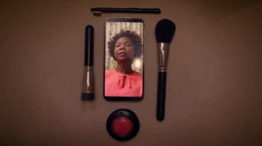 Makyaj malzemelerinin arasına yerleştirilmiş bir kadının ekran görüntüsü güzellik dersi ya da tartışma....
