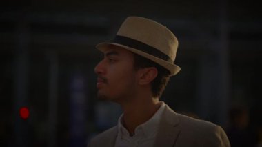 Şapkalı şık bir adam, sakin bir tavırla şehirli şehirlerdeki modern ve modaya uygun görünümleri resmeden mesafeye bakıyor.