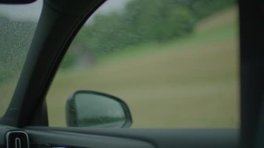 Yağmurlu bir arabanın penceresinden sakin bir kır manzarasına bakın, doğanın bulanıklığını yakalayın.