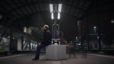 Modern tren istasyonunda gece karanlığında, modern mimarisi olan tek başına bir adam.
