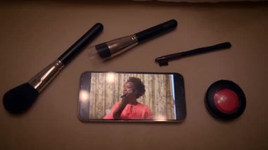 Makyaj üzerine bir video dersi, makyaj fırçaları ve kızaran, rehberlik eden güzellik teknikleriyle telefonda oynanıyor.