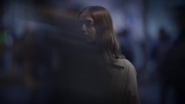 Karanlık çöktüğünde şehirde duran düşünceli bir kadın. Geçmişi bulanık bir yüz ifadesiyle..