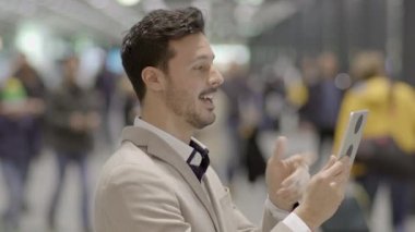 Takım elbiseli bir işadamı, çağdaş ofis ortamında mobil bir cihaz kullanarak onay veriyor.