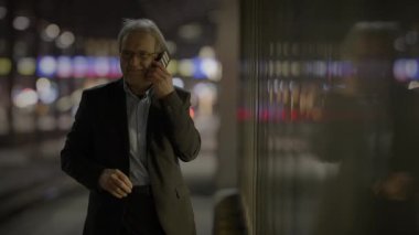 Kıdemli işadamı, gece bir şehirde modern bir şehir ortamında profesyonellik ve bağlantı sergiliyor.
