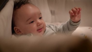 Samimi bir ortamda yatarken gülümseyen mutlu bir bebeğin yakın çekimi neşe ve masumiyet anı yakalıyor..