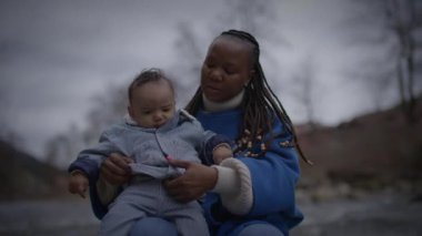 Bir anne ve bebek dışarıda huzurlu ve sevgi dolu anların tadını çıkarıyorlar, kışlık giysiler içinde.