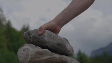 Bulutlu gökyüzü ve uzak ağaçlarla dolu bir ormanda taşları dengeleyen büyüleyici bir manzara huzur verici bir manzara yaratıyor..