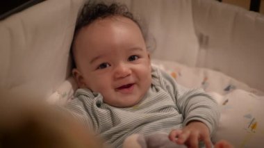 Beşikte yeşil pijamalı, kocaman bir gülümsemesi olan sevimli bir bebek. Aile ve bebek içeriği için mükemmel.