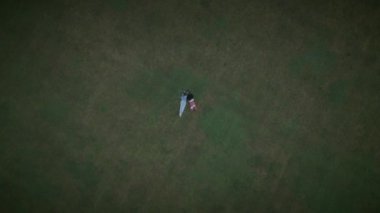Hava fotoğrafında, bir çift çimenli bir alanda rahatlarken görülüyor, huzur ve sükunet hissini iletiyorlar.