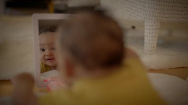 Sevimli bir bebek masum ve meraklı bir bakışla kendi yansımasına bakar. Neşeli bir merak anını yakalar.