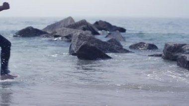 Deniz kenarındaki kayaların sakin ve sakin görüntüsü berrak bir gökyüzü altında huzurlu ve huzurlu bir zemin sunuyor.