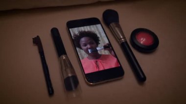 Akıllı telefondan makyaj dersi vermek, masadaki güzellik aletlerini göstermek, gerekli teknikleri göstermek.