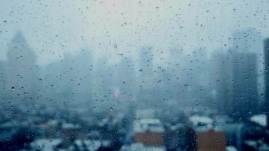 Yağmurlu bir günde yağmur damlalarıyla dolu bir pencereden gökyüzü manzarası karamsar bir atmosfer yaratır..