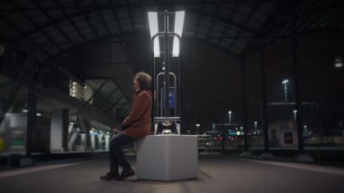 Gece bir tren istasyonunda, bir insan bir bankta oturur, derin düşüncelere dalmış, soğuk ve boş çevreyi hisseder.