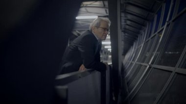 Profesyonel bir işadamı, geceleri modern bir ofis binasının yüksek bir noktasından dışarı bakıyor..