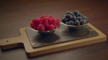 Böğürtlen ve ahududu karışımı ile dolu bir kase siyah mermer kesme tahtasına yerleştirilmiş ahşap saplı