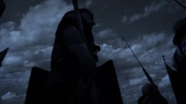 Mızraklı siluetli savaşçılar fırtınalı gece göğü altında savaşa hazır olun, tarihi çarpışmaya hazır olun.