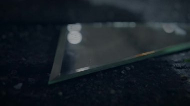 Kalıplaşmış karanlık bir yüzeyde duran üçgen bir cam parçasının belirsiz görüntüsü, karmaşık ayrıntılar gösteriyor.