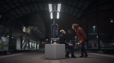 Bir tren istasyonunda, iki insan derin bir sohbete daldı modern şehir manzarasıyla çevrili, dinamik fikirler alışverişinde bulundular.