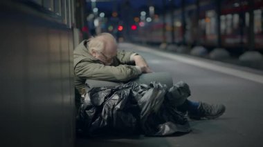 Geceleri ıssız bir tren istasyonunda oturan evsiz bir adam yalnızlığı ve kentsel zorlukları yansıtıyor..