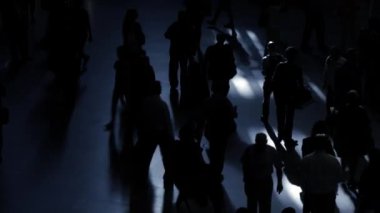 Loş bir ortamda, büyük bir grup insan ilginç siluetler yaratarak gizemli bir atmosfer yaratıyor.