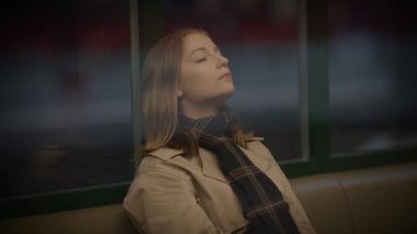 Paltolu ve atkılı kadın, otobüste ya da trende huzur içinde, şehirde huzur ve tefekkür yayıyor.