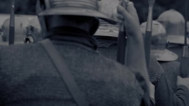 Askerlerin tek renkli görüntüsü. Tüfek taşıyorlar ve kask takıyorlar. Savaş sahnesini çağrıştırıyorlar..